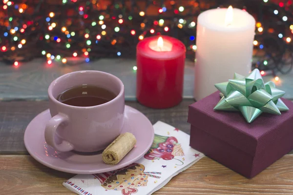 Праздничный натюрморт с чашкой чая, подарочной коробкой и горящими свечами — стоковое фото