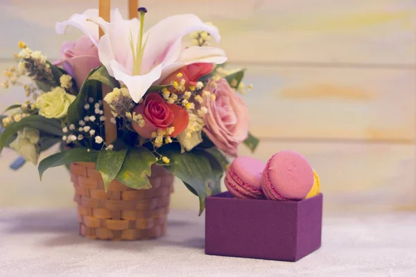 Una cesta de flores y una caja de macarrones — Foto de Stock