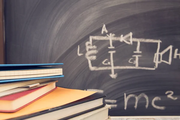 Physics lesson: Books on a black chalkboard — Stock Photo, Image