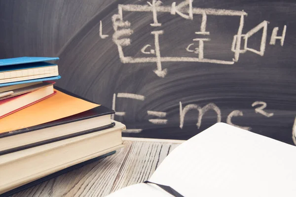 Physics lesson: Books on a black chalkboard — Stock Photo, Image