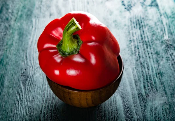 karanlık derin yeşil mavi masada ahşap kase kırmızı dolmalık biber