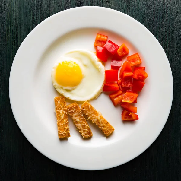 Sázená vejce na kulatý talíř s paprikou a sýrovými krutony — Stock fotografie