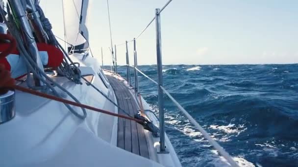 Seitenansicht des im offenen Meer fahrenden Segelbootes. weiße Jacht schwankt auf den blauen Wellen an einem sonnigen Tag. — Stockvideo