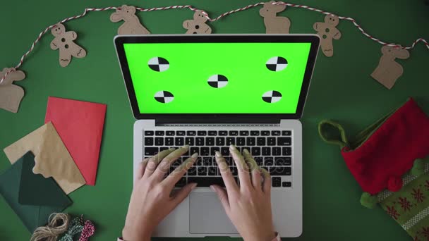 Kerst tabel bovenaanzicht op groene achtergrond. Vrouw handen te typen op het toetsenbord van de laptop. Groen scherm. Chromakey. Volgen van beweging — Stockvideo