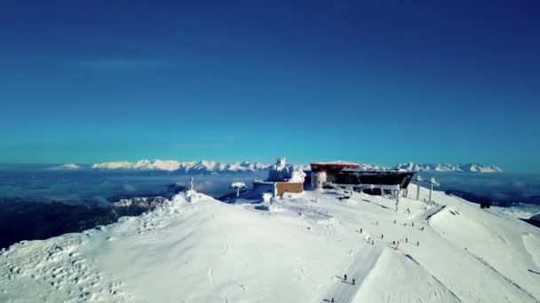 Вид с воздуха на лыжников на горнолыжном курорте в зимнем горном пике с реастаурантом в Словакии, Ясна Низке Татры. Вид сверху — стоковое видео