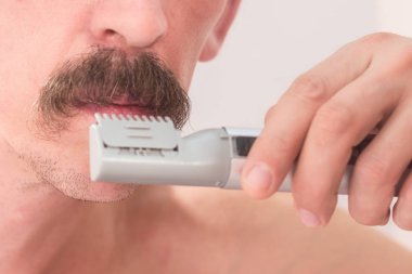 Tıraşsız bir adamın bıyığının bir düzeltici ile kesiyor. Yakın çekim.