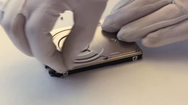 Een computertechnicus in witte handschoenen opent de cover van de harde schijf van de laptop. — Stockvideo