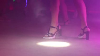 Topuklu yakın çekim parlak ışık ve duman ile bir gece kulübünde dans güzel bacaklı kız.