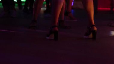 Kızlar bir gece kulübünde dans ediyor. Topuklu yakın çekim güzel bacaklarına.