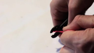 Adam kırmızı kabuk forseps kullanarak Tel kaldırır. Yakın çekim.