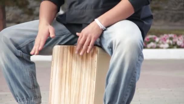 Een straat drummer muzikant speelt een percussie-instrument Cajon. — Stockvideo