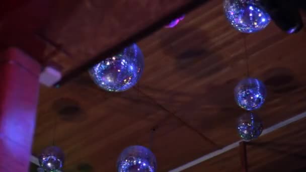 Spiegel ballen in een discotheek onder het plafond weerspiegelen lichtstralen van verschillende kleuren. — Stockvideo