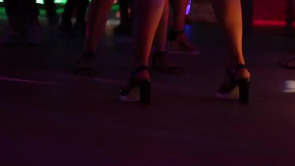 Girls are dancing in a nightclub. Beautiful legs on heels close-up.