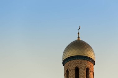 Altın bir gün batımı arka planda Camii kubbe. Tuğla, hilal ile altın bir minare.