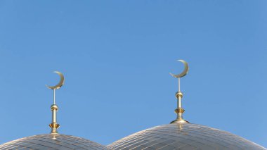 Mavi gökyüzünde bir caminin çatıda iki altın İslam hilal.