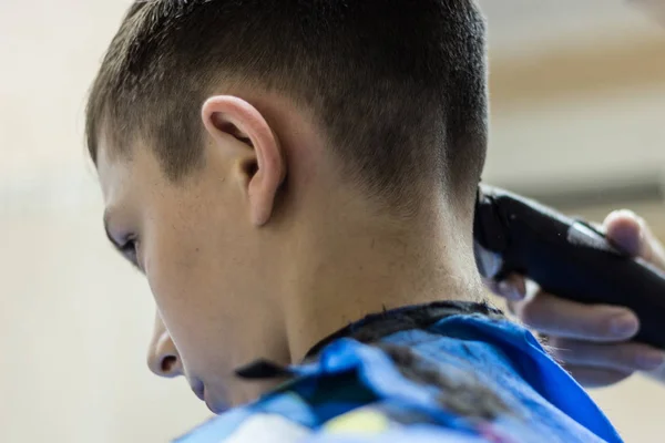 In the hairdressing salon, a teen is doing a haircut with a wireless razor. — Stock Photo, Image