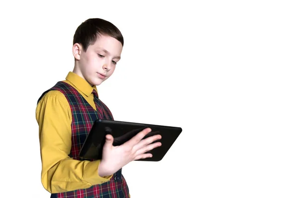 Um menino, um adolescente de colete xadrez, segura um tablet preto com uma mão. Isolado em branco . — Fotografia de Stock