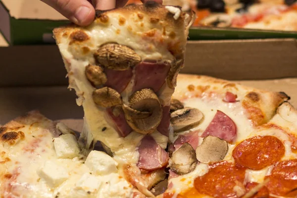 Человек берет кусок пиццы из коробки . — стоковое фото