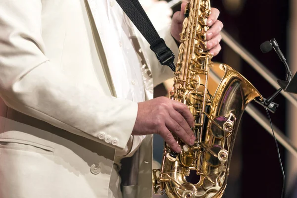 O saxofonista em um terno branco toca sozinho em um saxofone. Close-up . — Fotografia de Stock