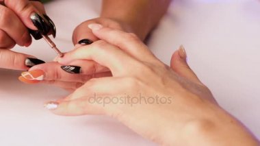 Manikürcü kadının tırnak üzerinde kahverengi bir vernik ile onun sol el orta parmak kapsar.