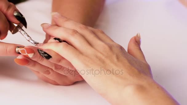 一个戴着黑色指甲的师在她手上的小指上用闪亮的清漆遮住了女孩的指甲。特写. — 图库视频影像