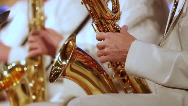 Крупним планом. Чоловік у білому костюмі грає саксофон у джазовому оркестрі. Невелика глибина різкості . — стокове відео