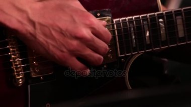 Bir elektro gitar çalarken erkek el yakın çekim.