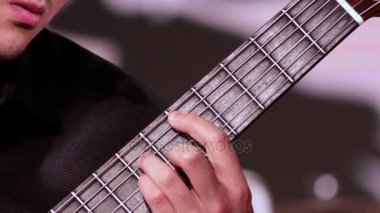 Bir adam gitar çalıyor. Bir close-up akorları fretboard üzerinde koyar sol el. Bir adam gitar çalıyor.