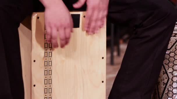 Een drummer muzikant speelt een percussie-instrument Cajon. Beelden op een muzikale thema. — Stockvideo