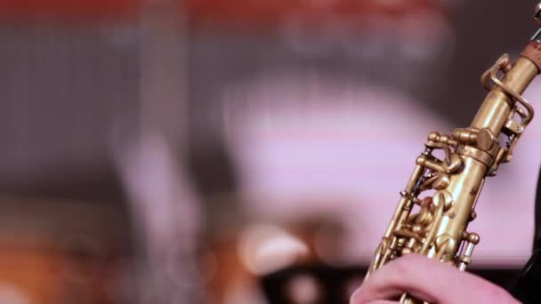 Comience el juego en un saxofón soprano instrumento de viento de madera. Un músico con barba y bigote toma una boquilla de un instrumento de viento en su boca y comienza a extraer los sonidos de la música . — Vídeo de stock