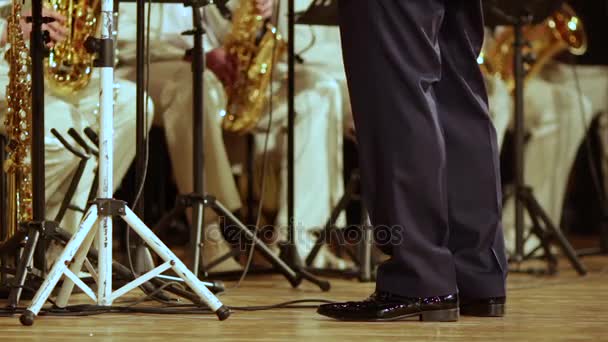 Benen av en blåsorkester dirigent i svarta byxor och patent skor. — Stockvideo