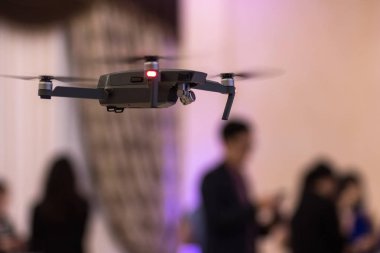 Arka plan bulanık kişilerle bir ziyafet salonunda siyah insansız quadrocopter çıkardı.