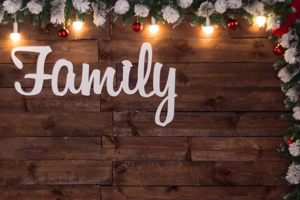 Textura fondo de madera con inscripción blanca Familia decorada con luces de Navidad y bolas rojas . —  Fotos de Stock