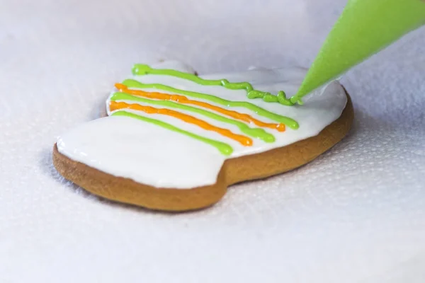 Decorating gingerbread with icing sugar using a green pipping bag. Handmade cookies in the form of a mitten. Christmas Treats.