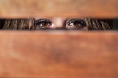 Kahverengi gözleri bir çatlak aracılığıyla ahşap kurulları arasında benzeyen güzel kız, uzun kirpik ile. Yakın çekim, copyspase.