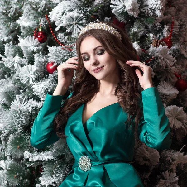 クリスマス ツリーの近くの彼女の頭の上の白い diadem と緑のドレスで長髪の美しい少女。正方形の写真. — ストック写真