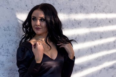 Işık perdeleri üzerinden çizgili dokulu bir duvara güzel tabaklanmış esmer kız modeli standları.