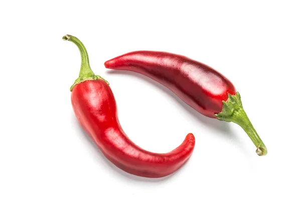 Dos chiles yacen uno frente al otro sobre un fondo blanco . — Foto de Stock