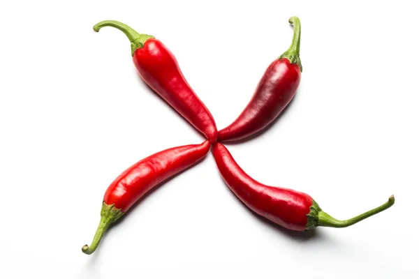 Cztery czerwone papryki chili w formie krzyża na białym tle. — Zdjęcie stockowe