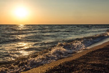 Deniz kıyısında arka planı güneşli gün batımı.