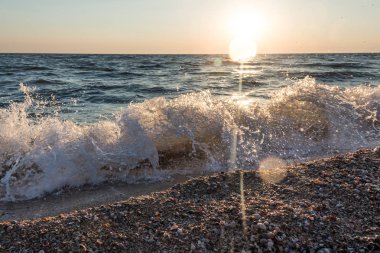 Bir deniz dalga kıyıya günbatımında atıyor..