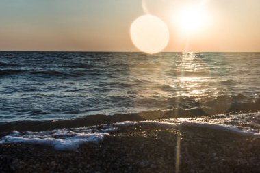 Bir deniz dalga kıyıya günbatımında atıyor..