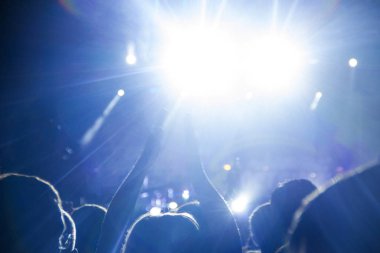 İnsanlar açık havada konser izlemek ve parlak mavi ışık onların el çırp.