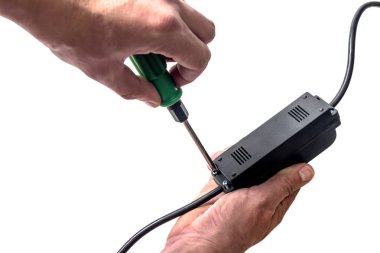 Bir adam bir tornavida bir elektronik cihaz üzerinde unscrews.