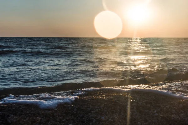 Bir deniz dalga kıyıya günbatımında atıyor..