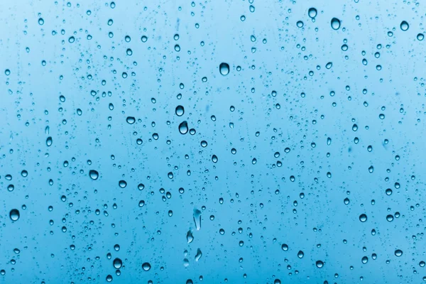 Grote regendruppels op een achtergrond van blauw glas. — Stockfoto