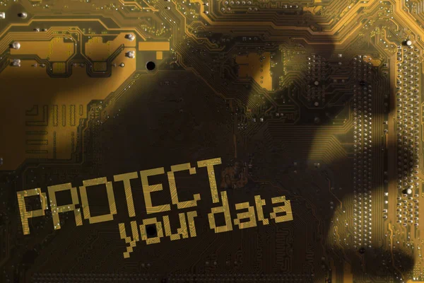 La inscripción "Protege tus datos" a través de la sombra de la mano en la placa madre amarilla . — Foto de Stock