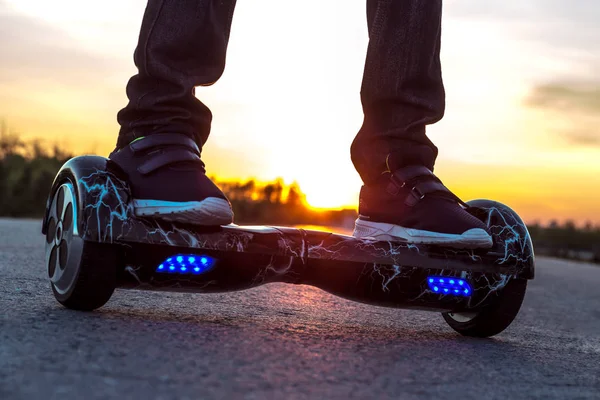 El tipo comenzó a moverse en la carretera en un segway de dos ruedas contra el atardecer . — Foto de Stock