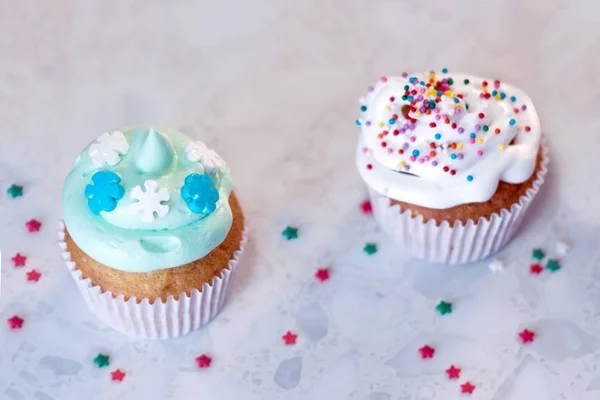 Dois cupcakes com decorações de creme e pastelaria em um fundo leve . — Fotografia de Stock
