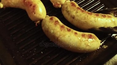 Maşa Kepçe ızgara bir siyah ızgara sosis döndürün. Yavaş mo.
